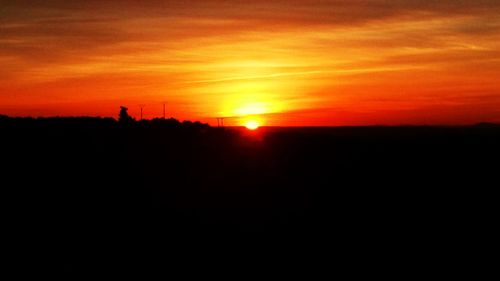 Scenic view of silhouette landscape against orange sky