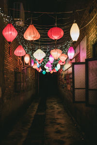 Illuminated lanterns hanging by building at night