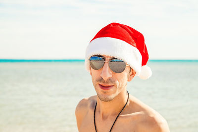 Portrait of young woman wearing sunglasses while standing at beach