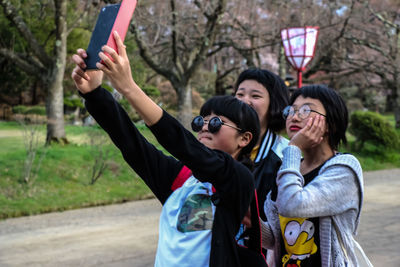 Happy young woman photographing with mobile phone