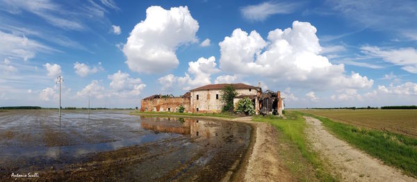 Panoramic view of old building by road against sky