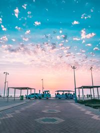 Street by sea against sky during sunset