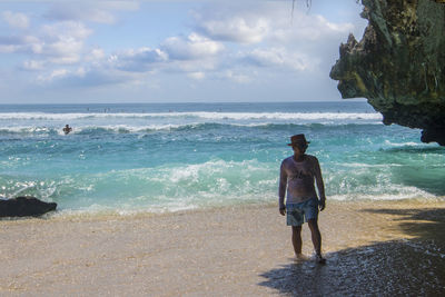 Man standing at beach against sky