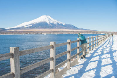 Rear view of person standing on promenade against snowcapped volcano