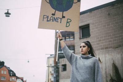 Female activist looking away while holding planet earth poster during social movement