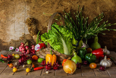 Still life with vegetables, herbs and fruits are beautifully placed on the wooden floor.