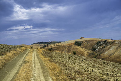 Road amidst field against sky