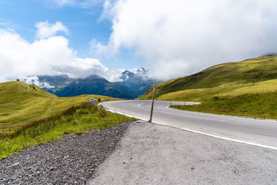 Empty road leading towards mountains against sky