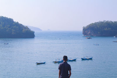 Rear view of man in sea against sky