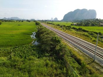 Railroad track amidst field against sky