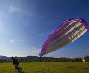 Man flying over field against sky