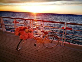 View of bicycle by sea against sky during sunset