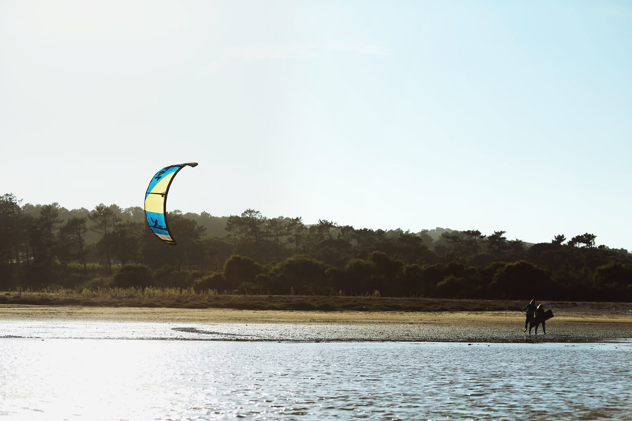 sky, nature, water, adventure, sport, plant, tree, waterfront, real people, extreme sports, beauty in nature, unrecognizable person, one person, day, scenics - nature, transportation, leisure activity, outdoors, parachute, kiteboarding