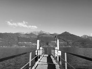 Pier leading towards mountains against sky