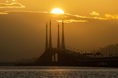 Bridge over river against sky during sunset