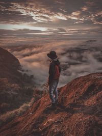 Man standing on mountain against sky during sunset