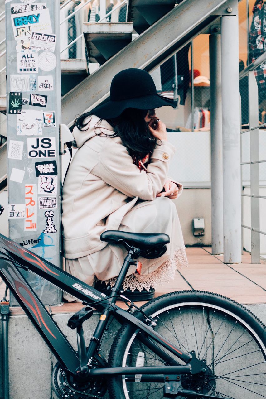 transportation, bicycle, real people, mode of transportation, one person, hat, lifestyles, clothing, land vehicle, architecture, leisure activity, city, young adult, casual clothing, women, day, adult, young women, looking, outdoors, hairstyle, riding, warm clothing