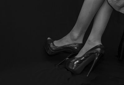 Low section of woman wearing high heels against black background