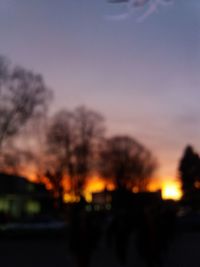 Defocused image of silhouette trees against sky during sunset