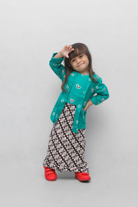 Portrait of smiling girl standing against white background