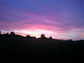 Silhouette of trees on landscape at sunset