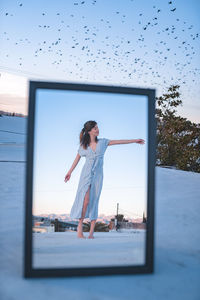 Woman standing with arms outstretched against clear sky