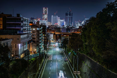 High angle view of illuminated street amidst buildings in city at night