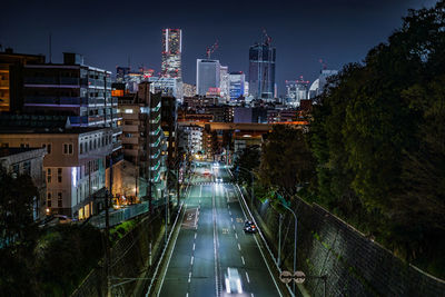 High angle view of illuminated street amidst buildings in city at night