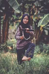 Portrait of young woman standing against plants