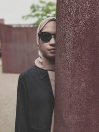 Portrait of young woman standing against wall