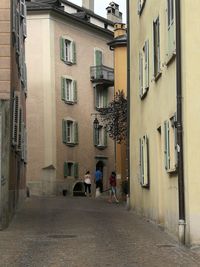 People walking on alley amidst buildings in city