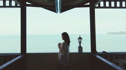 Rear view of woman looking at sea from balcony