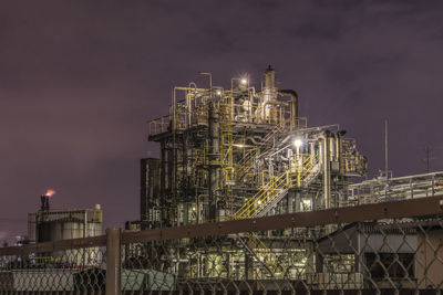 Illuminated factory against sky at night