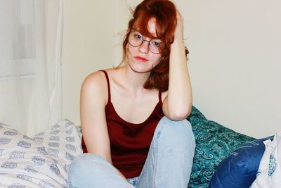 Portrait of young woman sitting on bed at home