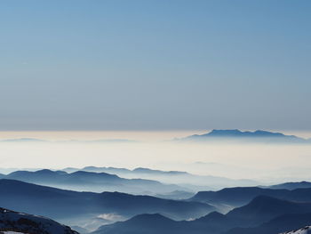 Scenic view of silhouette mountains against sky with fog