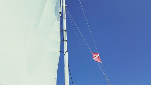 Low angle view of sailboat with flag against sky