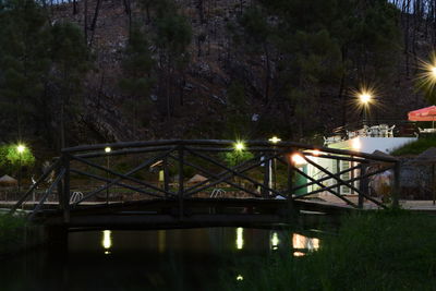 Illuminated bridge over river at night