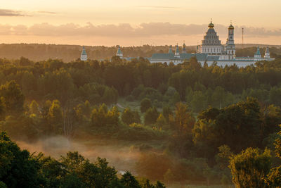 Panoramic view of trees and buildings against sky during sunset