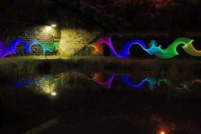 Multi colored water on illuminated tree at night