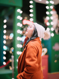 Rear view of young woman holding christmas tree at night