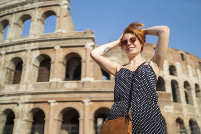 Cheerful traveler doing hair and smiling for camera