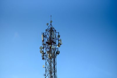 Low angle view of communications tower against clear blue sky