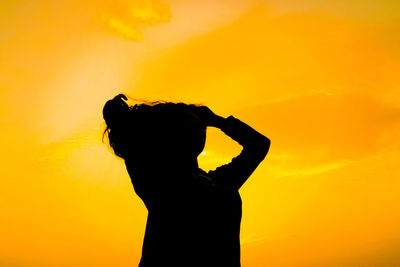 Silhouette woman standing against orange sky