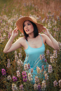 Young woman wearing hat sitting on field