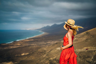 Woman standing on rock against sky