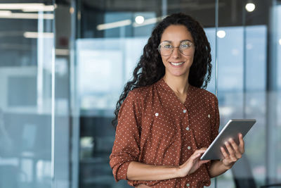 Portrait of young woman using mobile phone in office