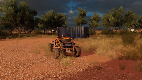 Abandoned car on field against trees