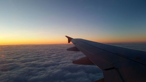 Airplane flying over sea against sky during sunset