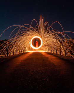 Man spinning wire wool on road at night