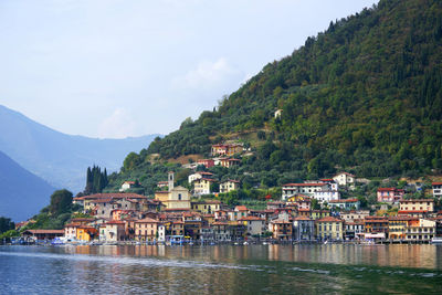 Houses by river in town against sky